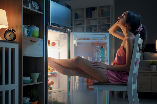 Mujer con calor refrescándose en una refrigeradora. 